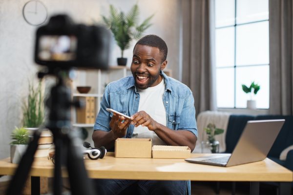 African man filming video while unpacking new smartphone