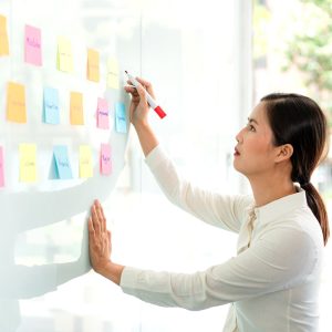 Businesswoman executive writing and taking notes keyword on board wall to planning about a business