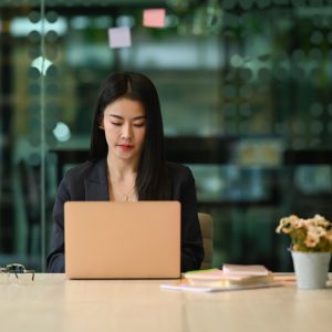 Millennial female entrepreneur typing business email, working online on her laptop computer.