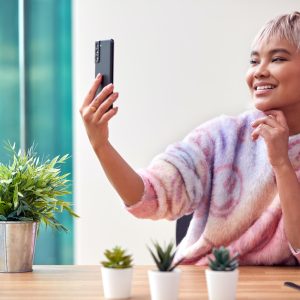 Woman At Home Taking Selfie On Mobile Phone To Post On Social Media