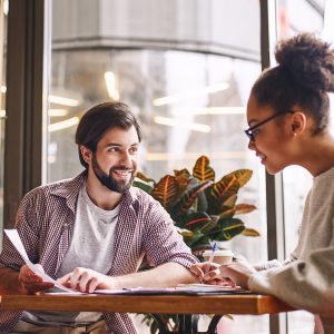 Writting down new ideas. Bearded businessman pointing at chart with smile and discussing something