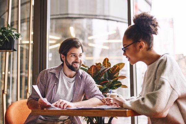 Writting down new ideas. Bearded businessman pointing at chart with smile and discussing something